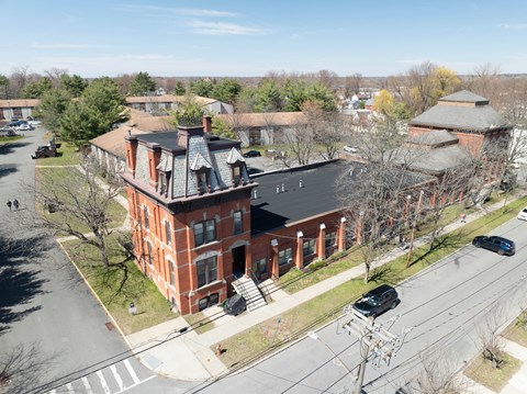 A large red brick building with a black roof and a tower with a dome on top.