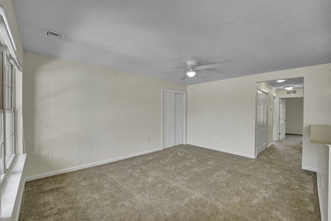 A spacious room with a carpeted floor and a ceiling fan.