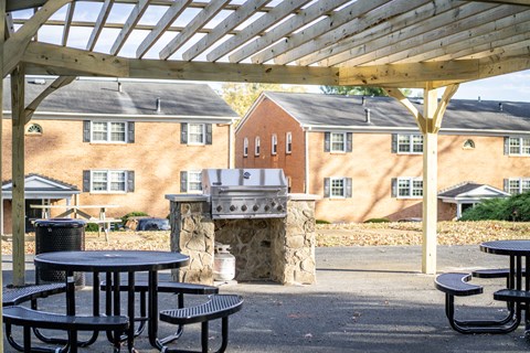 A patio with tables and a fireplace in front of a brick building.