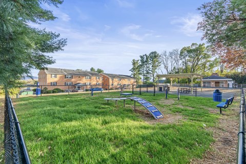 A park with a playground and a building in the background.