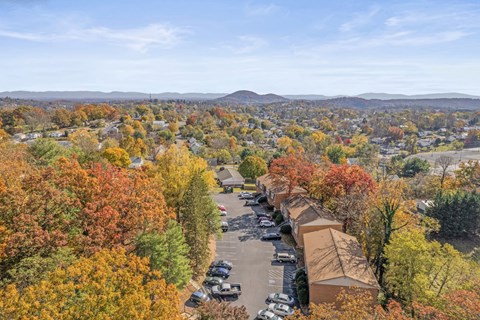 A view of a residential area with a parking lot and houses surrounded by trees with autumn foliage.