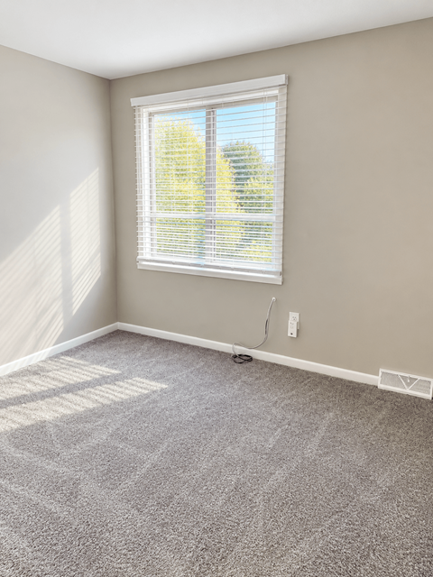 A room with a window covered by white blinds.