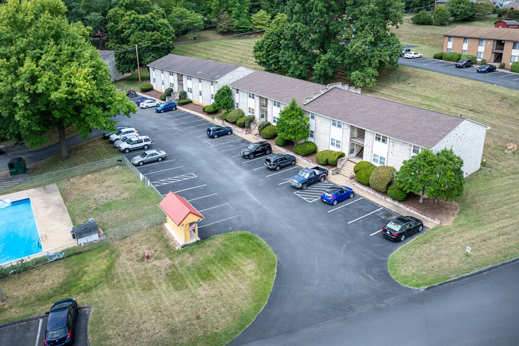A parking lot with cars and a small pool area in front of apartment buildings.