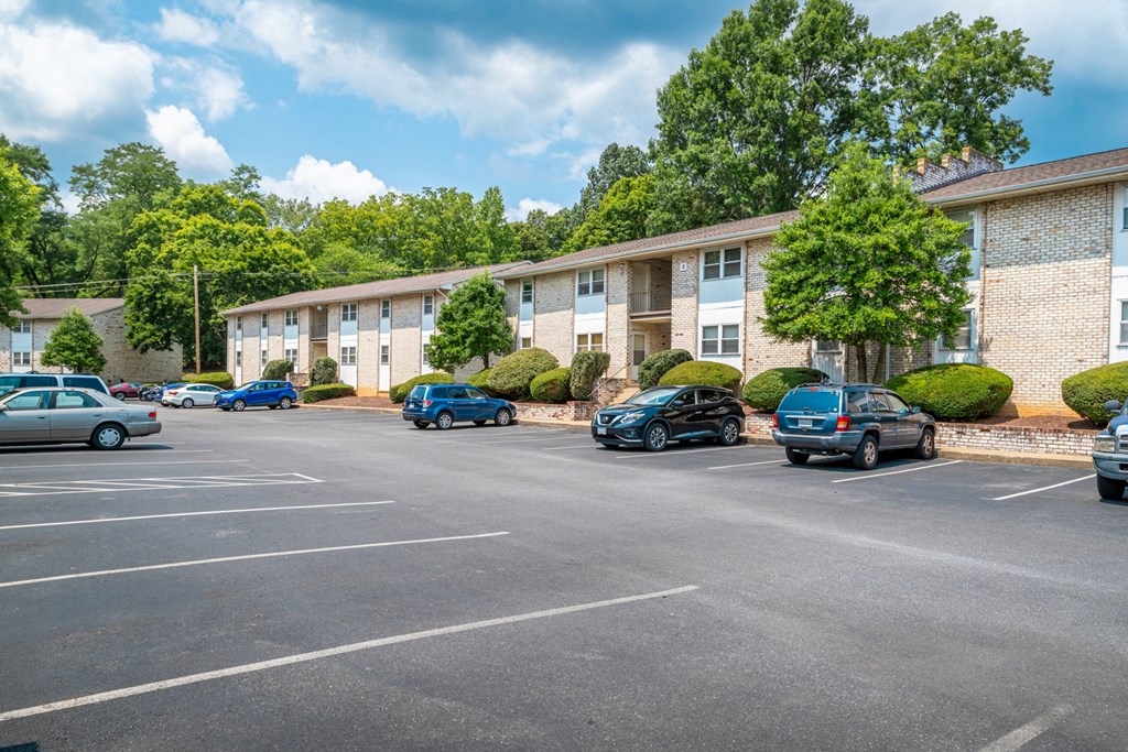 A parking lot with cars and apartment buildings in the background.