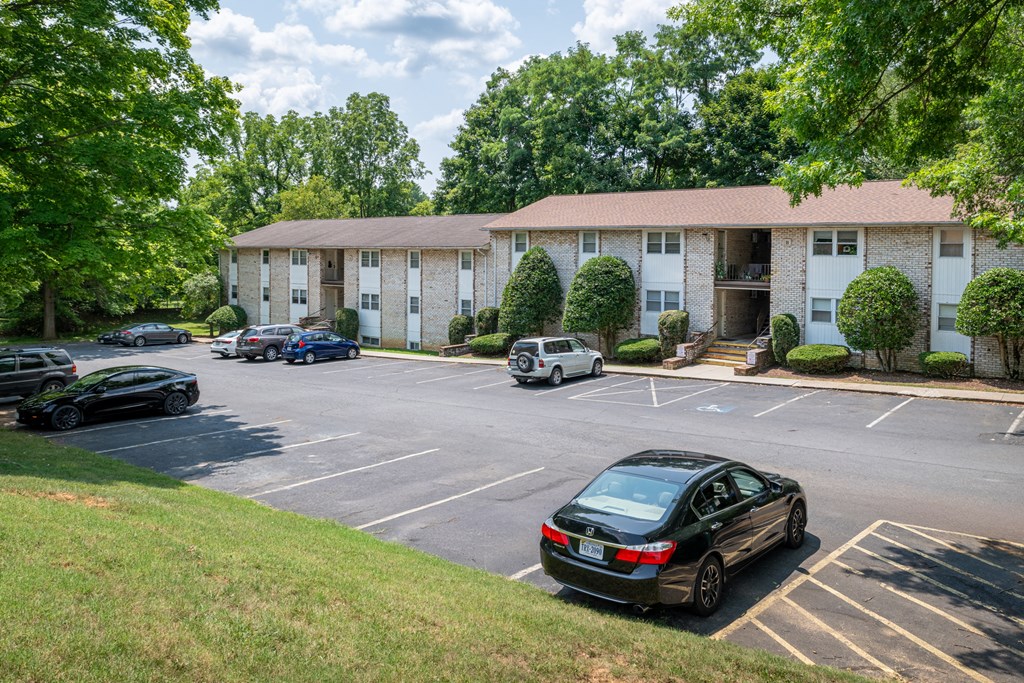 A black car is parked in a parking lot in front of a building.