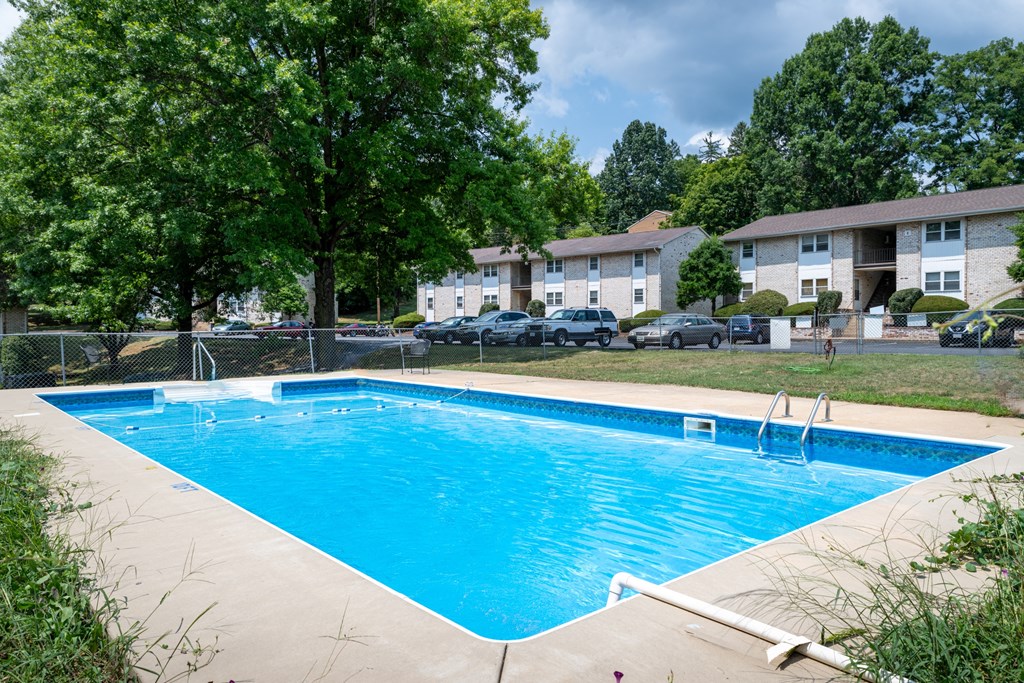 A swimming pool surrounded by trees and apartment buildings.