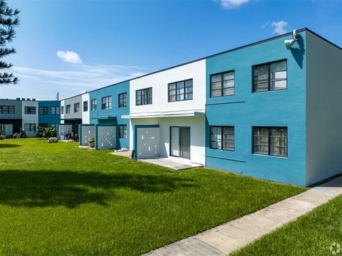 a row of blue and white houses on a green lawn