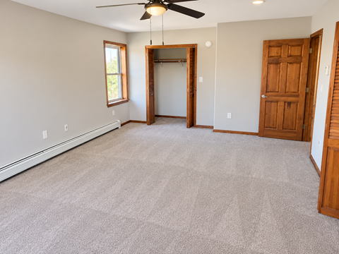 A room with a ceiling fan and a doorway leading to another room.