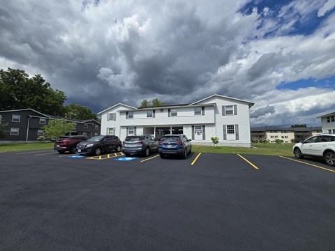 A parking lot with cars and a white building in the background.