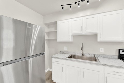 A modern kitchen with a stainless steel refrigerator and white cabinets.