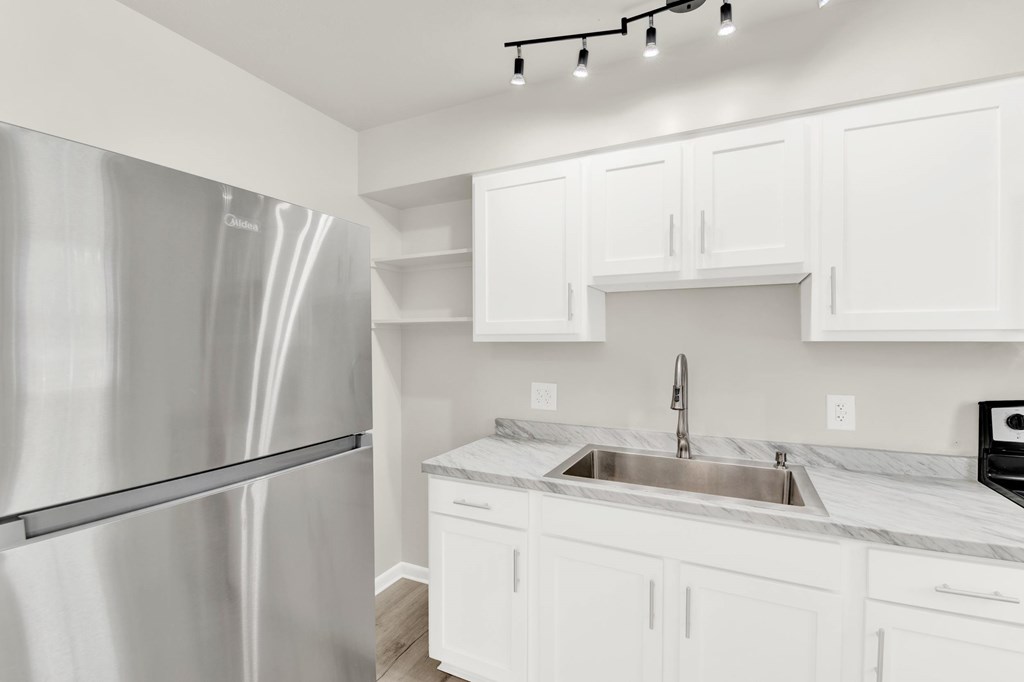 A modern kitchen with a stainless steel refrigerator and white cabinets.