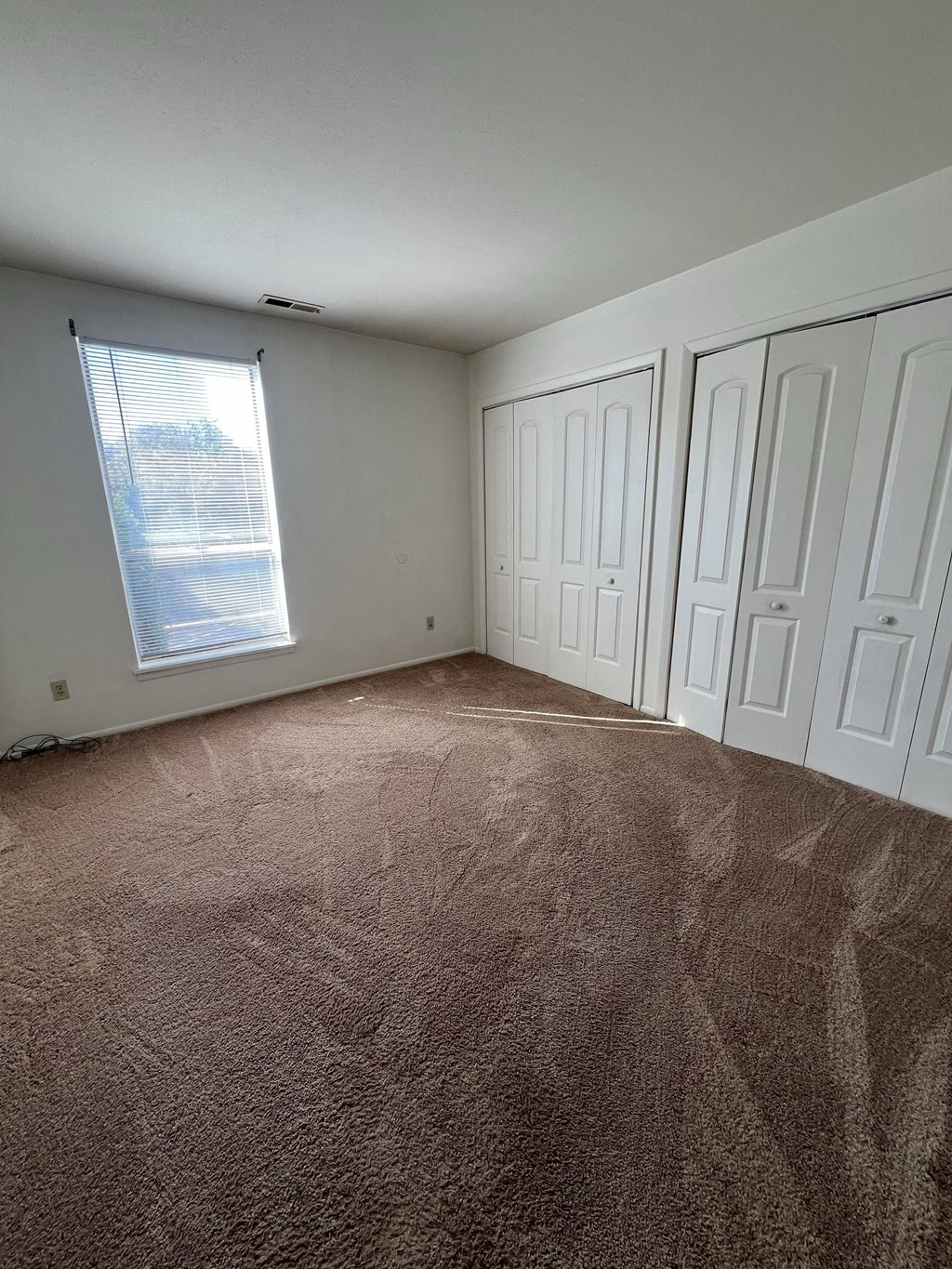 the living room of an empty house with carpet and a window