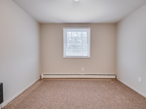 A room with a carpeted floor and a window.