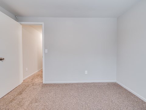 A room with a carpeted floor and a doorway leading to another room.