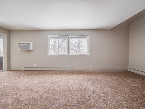 A room with a carpeted floor and a window showing a snowy landscape outside.