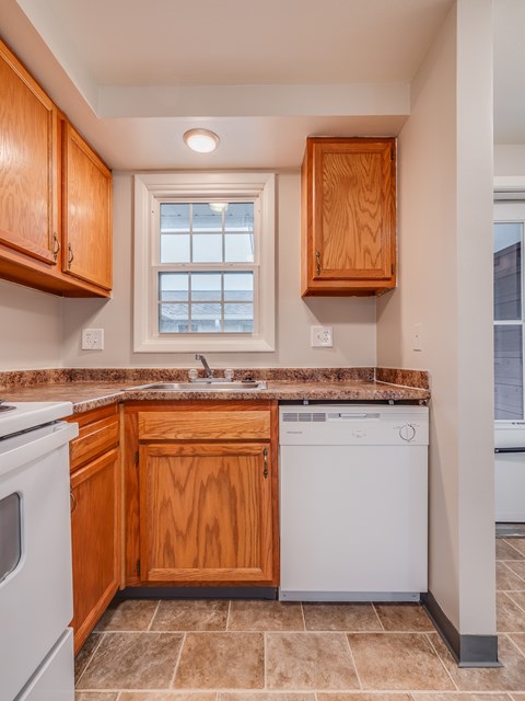 A kitchen with wooden cabinets and a white dishwasher.