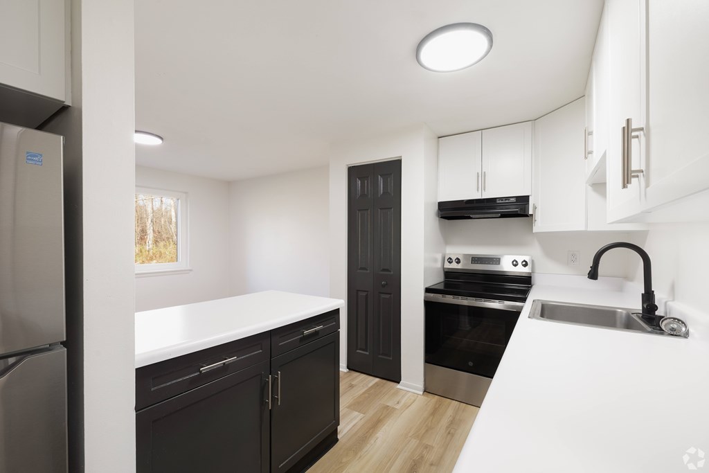 A modern kitchen with a refrigerator, oven, and sink.