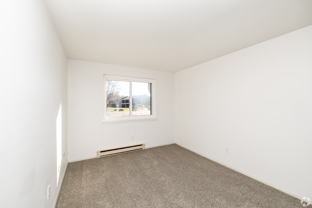 A room with a window and a car parked outside.