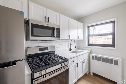 A white kitchen with a stove, oven, microwave, and refrigerator.