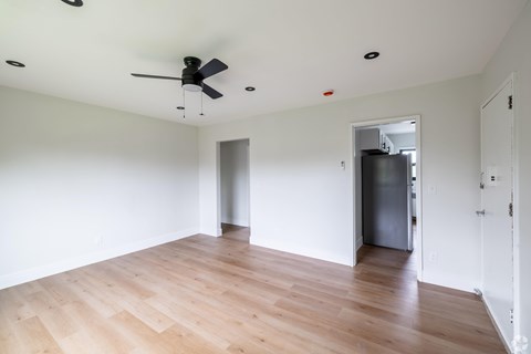 A room with a ceiling fan and wooden flooring.