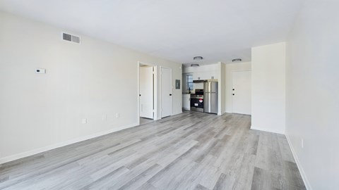 A spacious room with a kitchen area in the background.