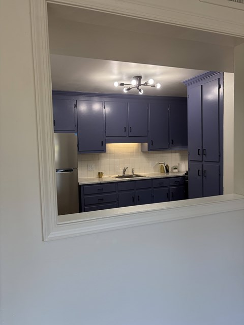 A kitchen with purple cabinets and a fridge.