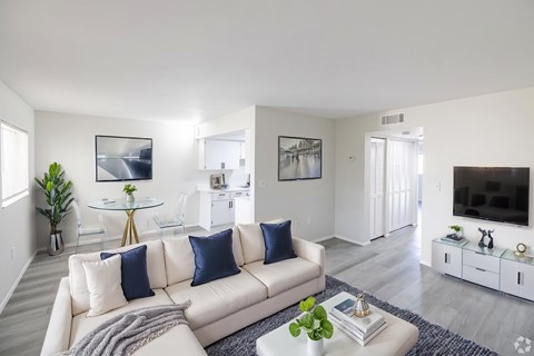 A living room with a white couch and a glass coffee table.
