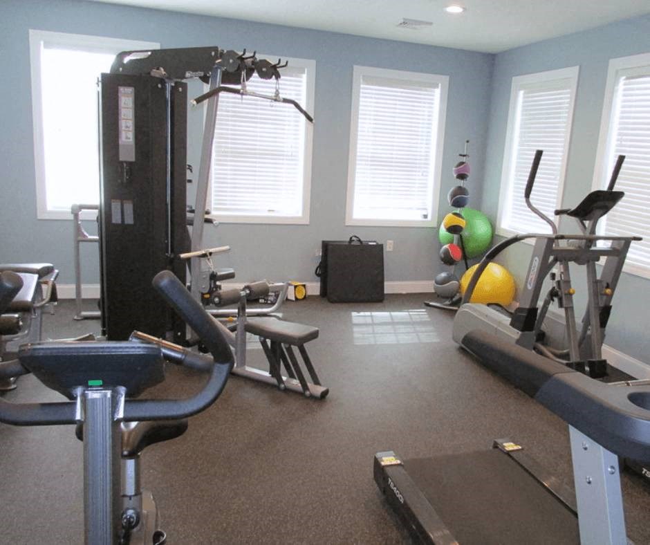 a gym with exercise equipment in a room with windows