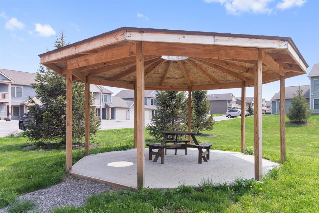 a picnic table under a wooden pavilion in a yard