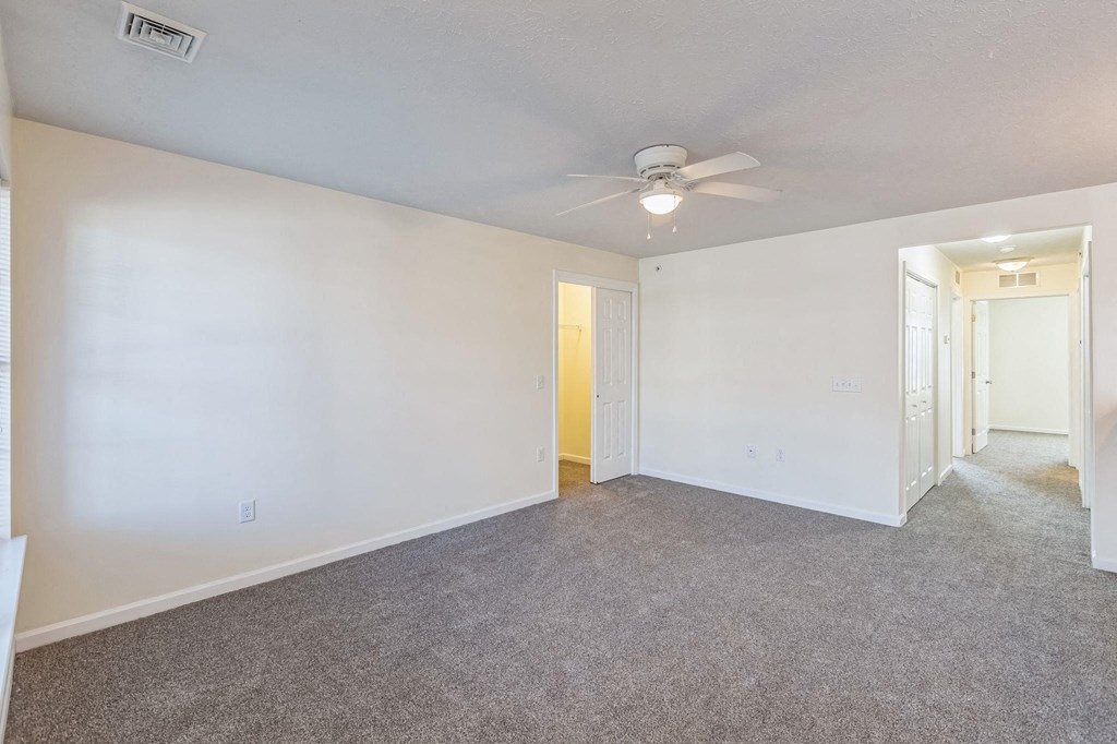 an empty living room with white walls and a ceiling fan