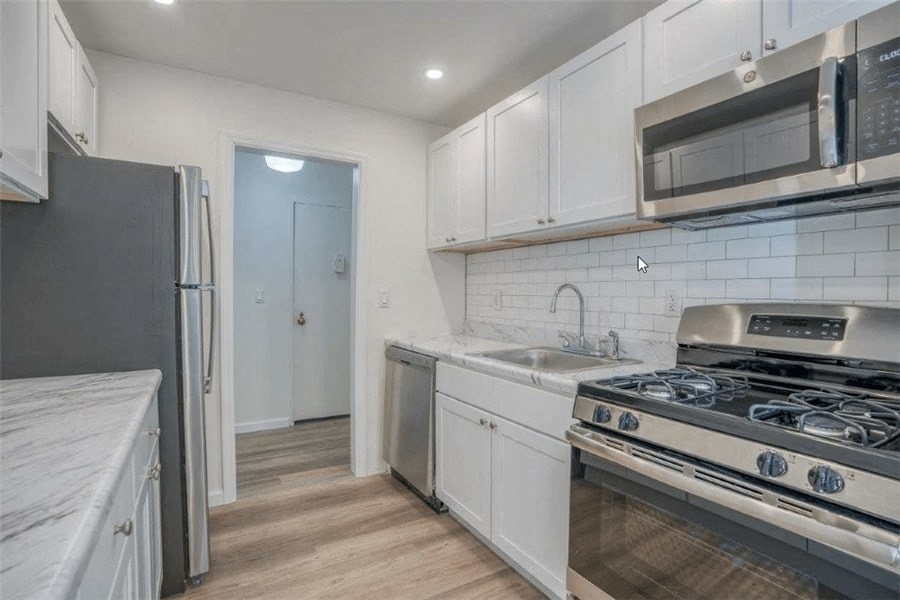 a kitchen with white cabinets and stainless steel appliances
