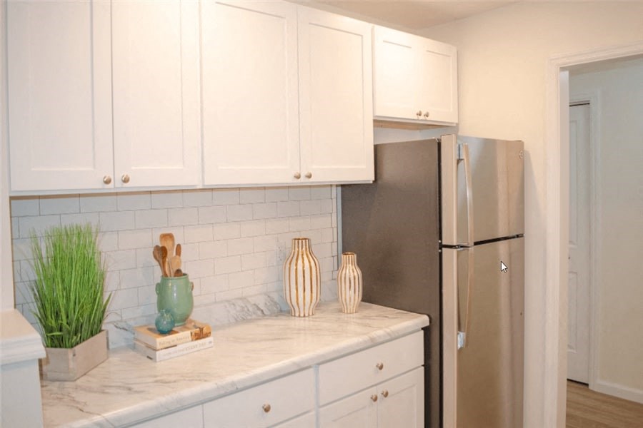 a kitchen with white cabinets and a refrigerator