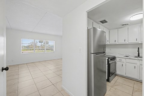A kitchen with white cabinets and a stainless steel refrigerator.