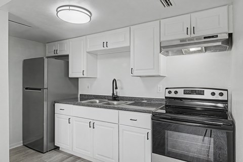A black and white photo of a kitchen with white cabinets and a black stove.