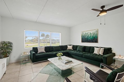 A living room with a green couch and a ceiling fan.