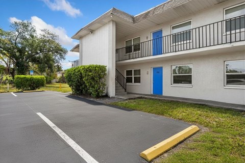 A white building with a blue door and a yellow barrier in front.