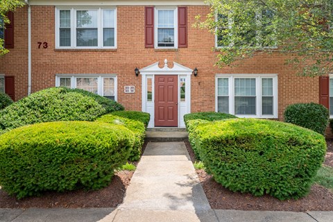 A red brick house with a white door and windows.
