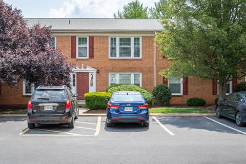 A blue car is parked in a parking lot in front of a brick building.