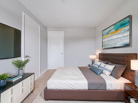 A bedroom with a large bed and a painting on the wall.