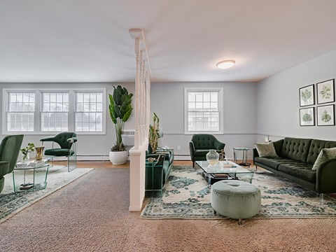 A living room with a green couch and a glass table.