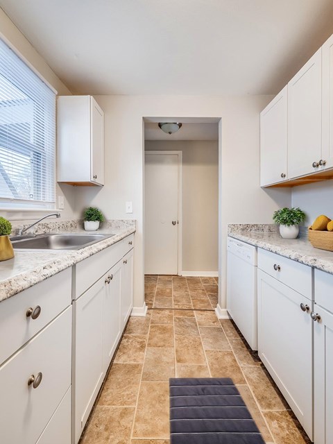 A kitchen with white cabinets and a tiled floor.