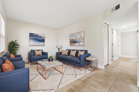 A living room with blue couches and a white rug.
