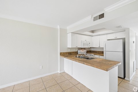 A kitchen with white cabinets and a wooden island.