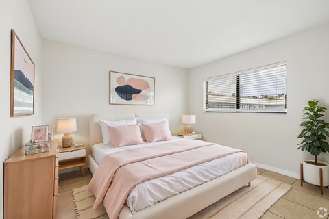 A bedroom with a large bed and a potted plant.