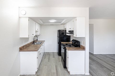 A kitchen with white cabinets and a brown countertop.