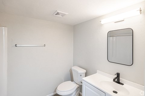 A white toilet sits next to a white sink in a small bathroom.