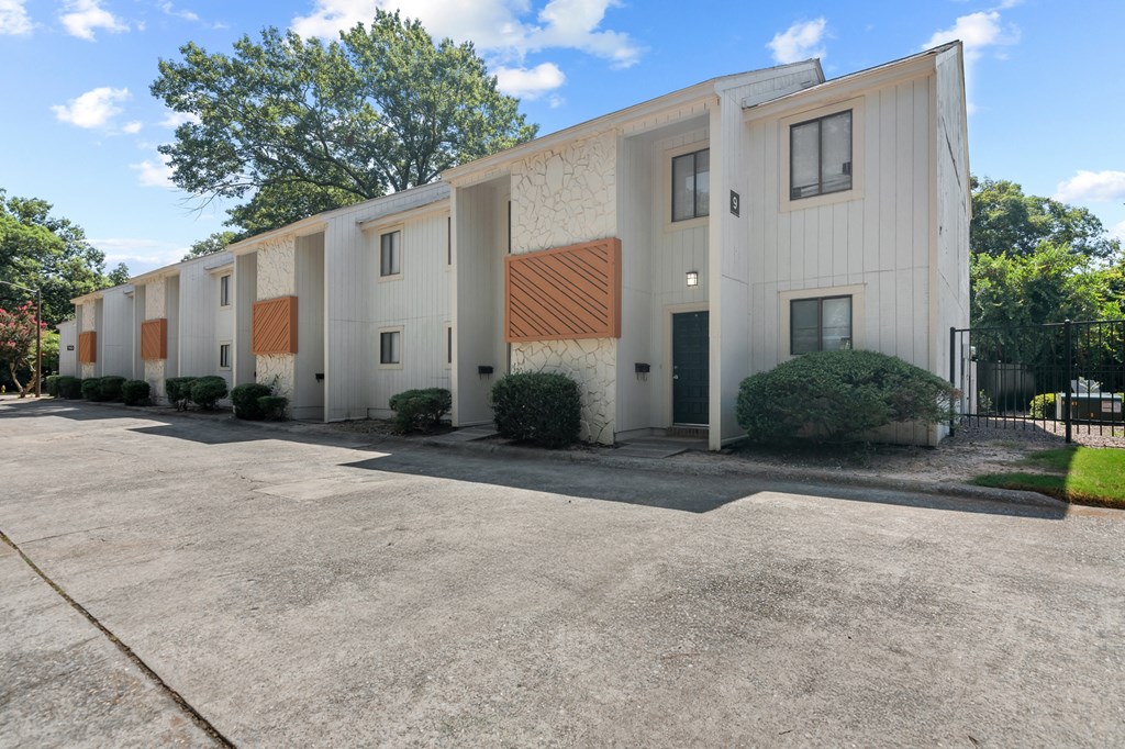 A building with a white and brown exterior is surrounded by a parking lot.