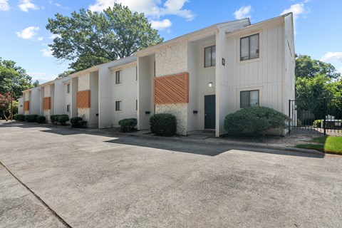 A building with a white and brown exterior is surrounded by a parking lot.