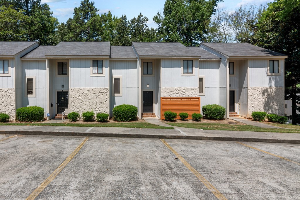 A parking lot in front of a building with four houses.