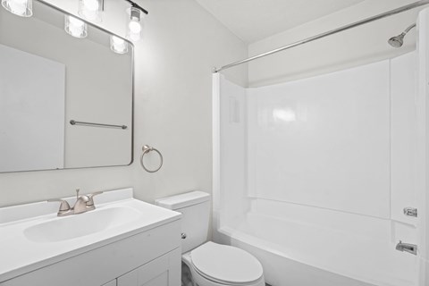 A white bathroom with a toilet, sink, and shower.